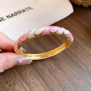 Macro detail of a vintage gold-toned bangle featuring pink and white resin swirls