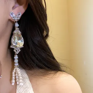 Detailed close-up of elegant silver needle drop earrings with rhinestones and pearl tassels