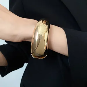 Vista dettagliata di un bracciale a polsino grosso in oro lucido irregolare sul polso.