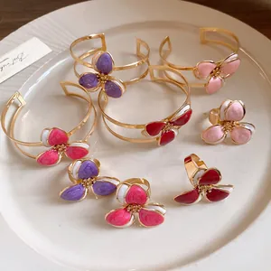 Close-up of elegant flower rings and bangles with colorful enamel petals on a plate