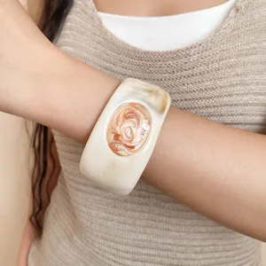Detailed view of a wide vintage resin bangle with marbled pattern and carved rose motif