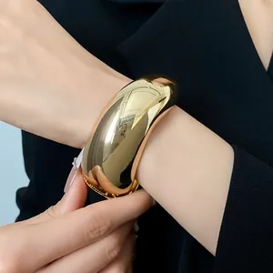 Dettaglio di un moderno bracciale rigido dorato liscio irregolare su un polso