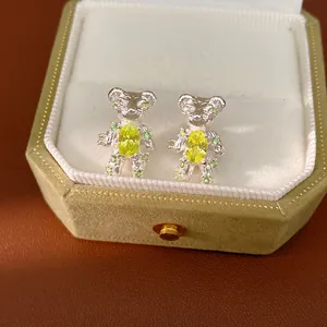 Close-up of cute silver bear stud earrings featuring yellow and green zircon stones