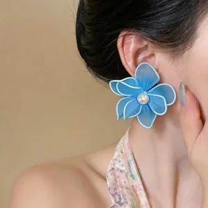 Detail shot of elegant blue mesh flower stud earrings with pearl center on model