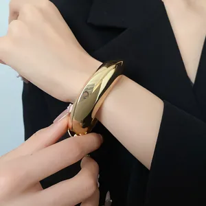 Dettaglio di un bracciale a fascia dorato irregolare indossato con un elegante blazer nero