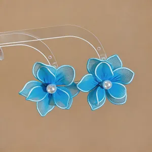 Detail view showing the intricate blue mesh petals and pearl center of these floral earrings.