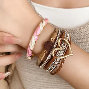 Close-up detail of a multi-layer leather bracelet with a gold heart and rhinestone accents.