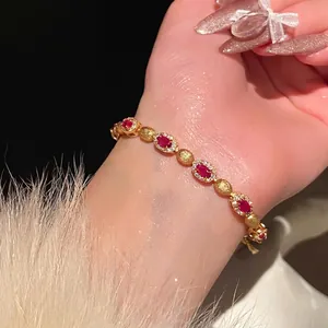 Detail shot of elegant gold-plated zircon bracelet featuring red oval stones on wrist