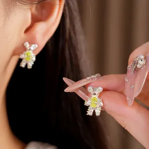 Close-up detail of silver bear stud earrings with green zircon insets on model's ear