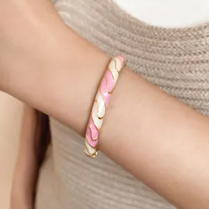 Detailed macro view of a vintage pink and cream enamel wave pattern bangle on wrist