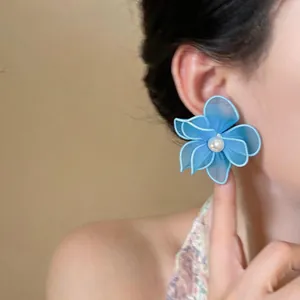 Detailed view of elegant blue mesh flower earrings with central pearl on model