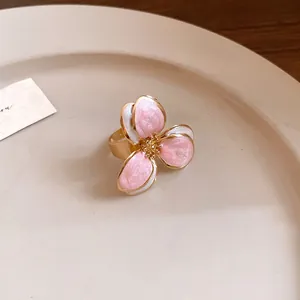 Close-up of vintage style pink and white enamel flower ring on a beige plate
