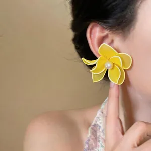 Beautiful detail view of an elegant yellow mesh flower pearl earring on a model's ear