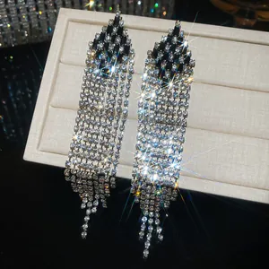 Close-up of luxury rhombus tassel earrings with sparkling rhinestones and silver needles.