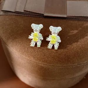 Macro shot of cute silver bear stud earrings with yellow and green zircon stones.