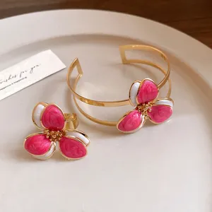 Detailed view of an elegant pink enamel flower ring and open cuff bracelet jewelry set