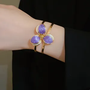 Detailed macro view of vintage gold cuff bracelet with purple enamel flower design
