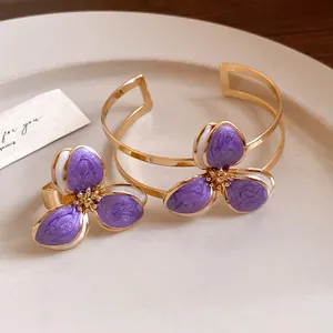 Elegant vintage purple enamel flower jewelry set featuring gold cuff bracelet and ring