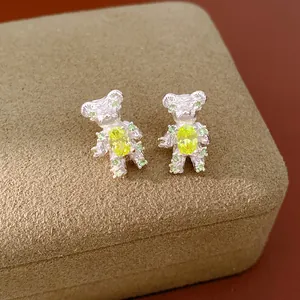 Detail view of cute zircon bear stud earrings with yellow and green gemstones on box