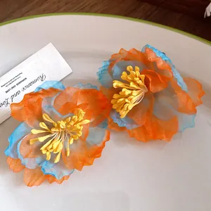 Detailed macro view of bohemian chiffon flower stud earrings in orange and blue