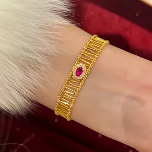 Detailed macro view of a vintage-style gold bracelet featuring a radiant central red zircon