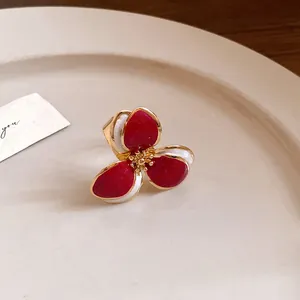Detailed close-up of a red enamel flower ring featuring vintage gold-tone petals