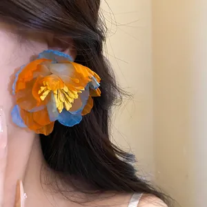 Close-up of bohemian style chiffon flower earrings in vibrant blue and orange hues.