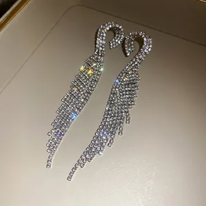 Close-up of elegant sparkling swan-shaped long tassel earrings with glittering rhinestones