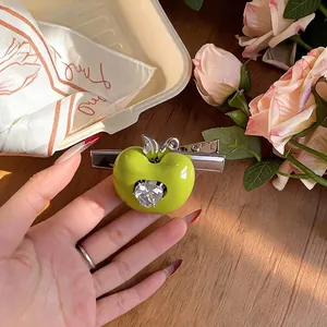 Barrette à cheveux pomme verte en résine avec zircon en cœur sur un fond de bois