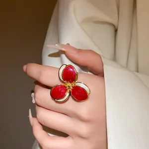Detailed macro view of a vintage court style red enamel flower ring worn on a finger