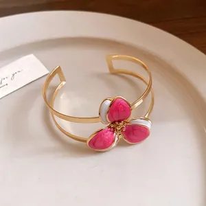 Detail of vintage gold-tone cuff bracelet with pink enamel flower on a ceramic plate