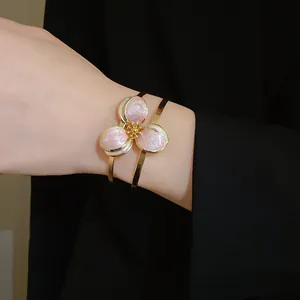 Close-up of vintage gold bangle with delicate pink enamel three-petal flower detail