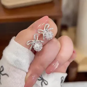 Detailed macro view of elegant silver bowknot stud earrings with a sparkling zircon ball