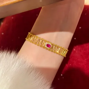 Detailed view of a gold-tone vintage bracelet featuring a central red gemstone on a wrist