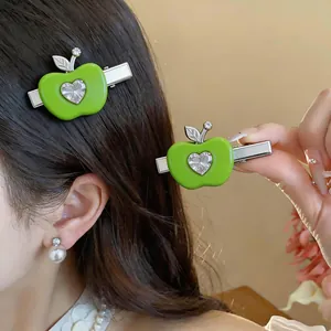 Gros plan détaillé d'une pince à cheveux pomme verte avec zircon en forme de cœur