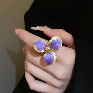 Detailed macro view of a vintage purple and gold floral enamel ring on a finger.