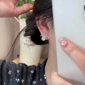 Detail view of French style zircon bow stud earring on model's ear