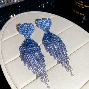 Close-up of blue gradient rhinestone tassel earrings with heart studs on a display box.