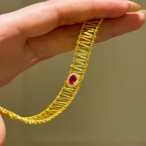 Macro view of gold openwork bracelet featuring an oval red zircon center stone