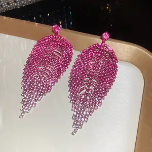Close-up detail of fuchsia rhinestone fringe earrings showcasing sparkling tiered leaf design.