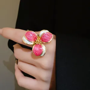 Close-up detail of a vintage pink and white enamel flower open ring with gold metallic edges