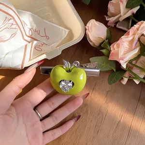 Gros plan sur la pince à cheveux pomme verte avec un zircon brillant en forme de cœur.