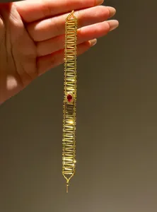 Detail view of vintage gold hollow bracelet with oval red zircon and pavé setting