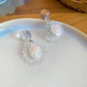 Dettaglio di orecchini a margherita trasparenti iridescenti con motivi a rosa