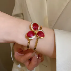 Close-up of a vintage floral open bangle featuring red and white oil drip glitter petals.