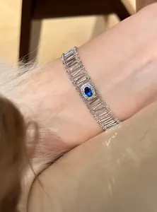 Close-up of silver-tone hollow bracelet with oval blue stone and zirconia accents