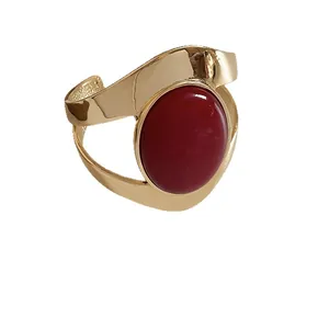 Elegant gold-tone metal cuff bracelet featuring a large oval red stone centerpiece