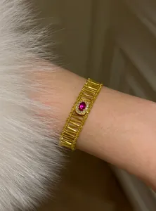 Close-up detail of a vintage gold-toned bracelet with red oval zircon and openwork design