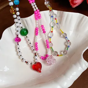 Gros plan de colliers de perles colorées avec pendentifs cœur dans un bol coquille