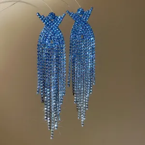 Macro view of glittering blue rhinestone tassels on elegant silver needle earrings